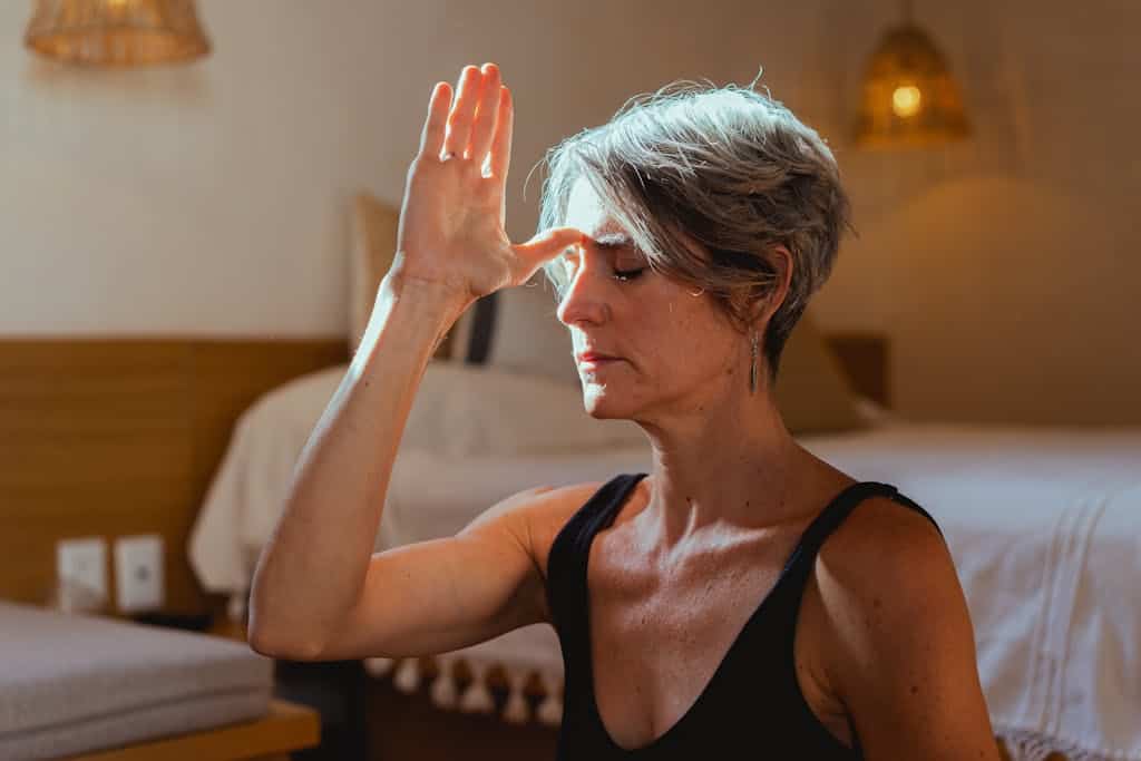 Serene elderly woman practicing yoga meditation indoors, symbolizing wellness and positive aging.