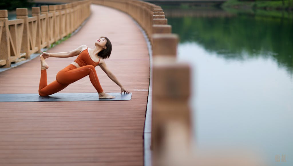 Woman doing yoga on a bridge, showcasing flexibility and mindfulness in a serene outdoor setting.