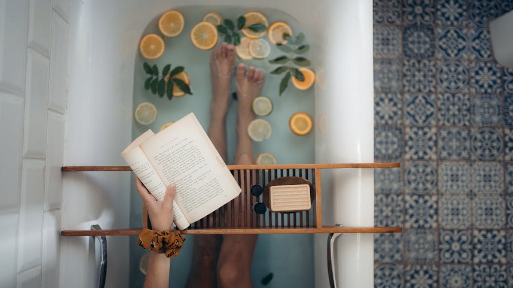 A tranquil bathtub with citrus fruits, book, and self-care essentials for relaxation.